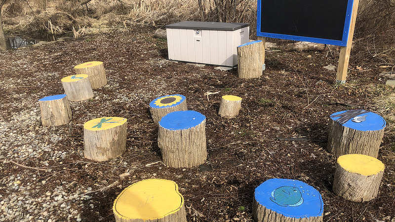 Colorful painted tree stumps serve as seating in an outdoor classroom.