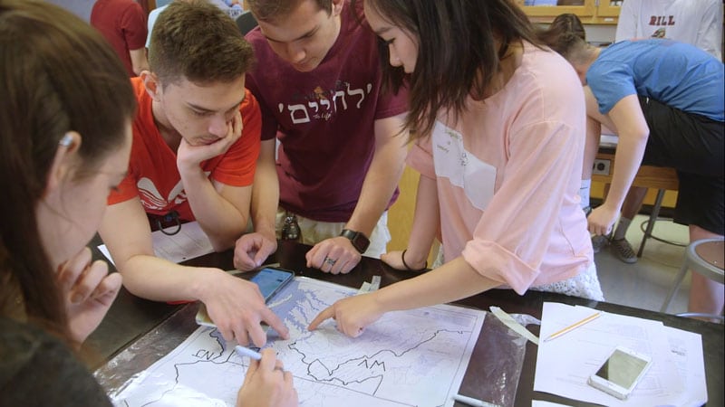 Four high school students using a watershed map in a classroom.