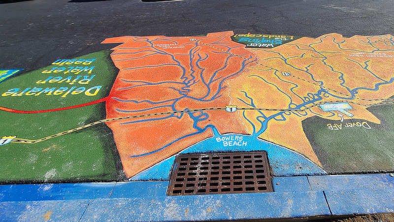 Pavement near a storm drain painted to show the local watershed.