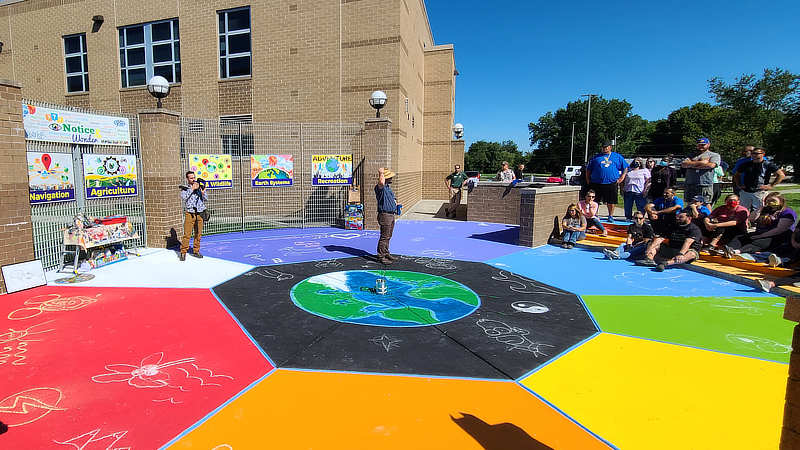 People sitting on the edge of a brightly painted courtyard with chalk art.