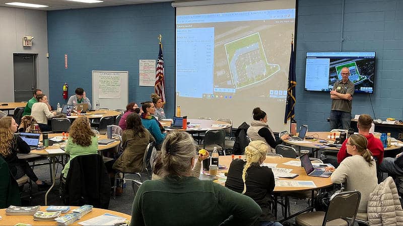Educators seated at tables observing a Model My Watershed demonstration.