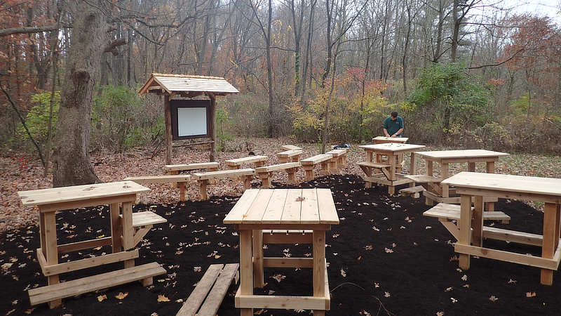 Outdoor classroom with wooden tables and kiosk.
