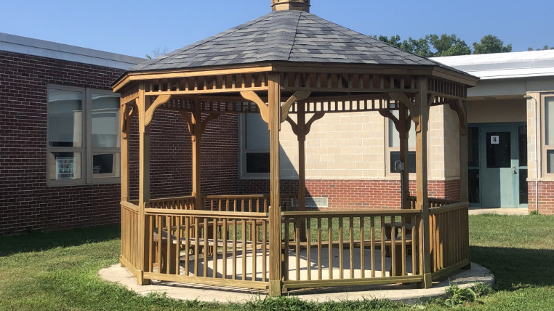 A gazebo with benches serves as an outdoor learning space at a school.
