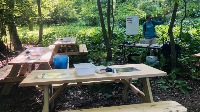 Tables in an outdoor learning station set up for macroinvertebrate identification.